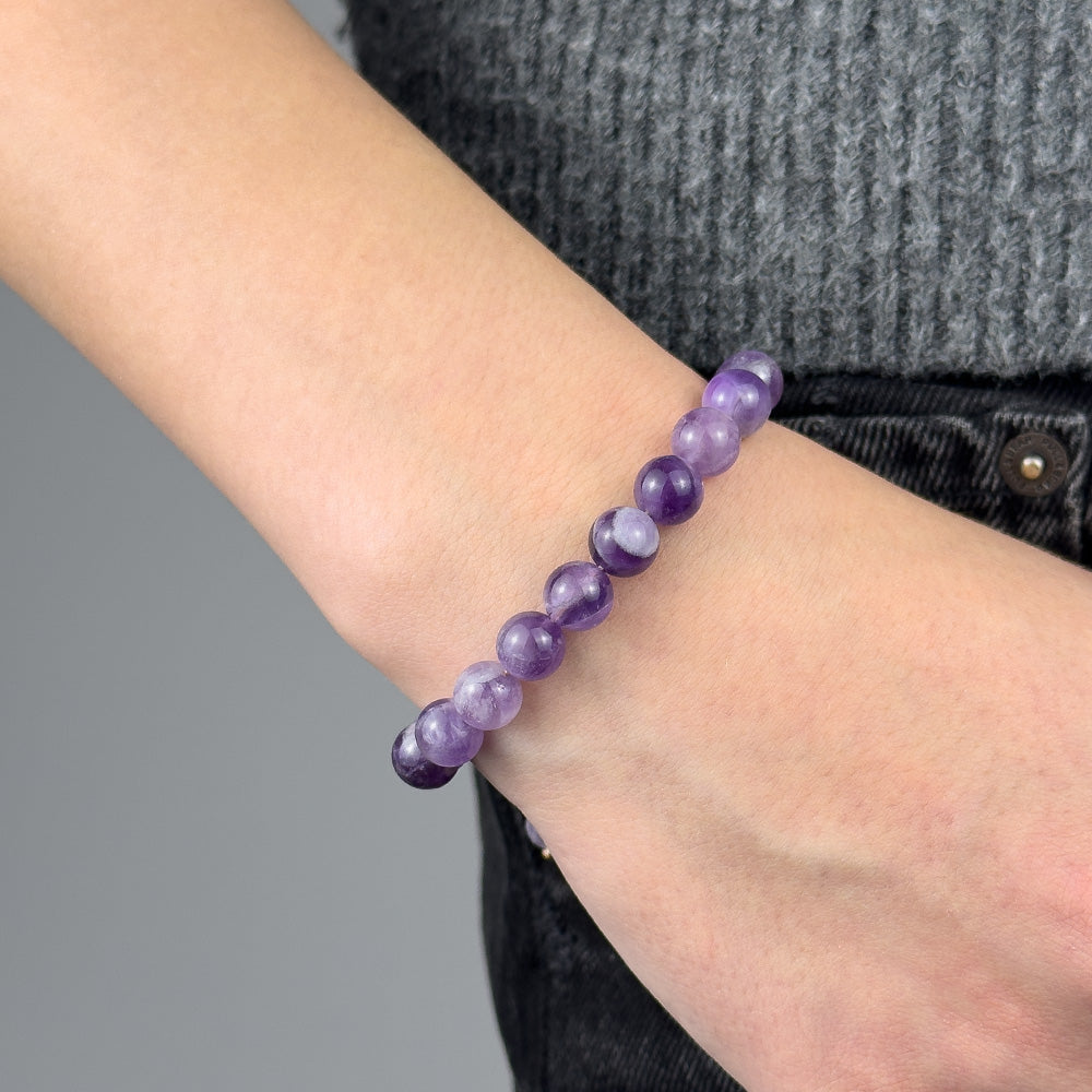 Purple beaded bracelet on a wrist with a gray background