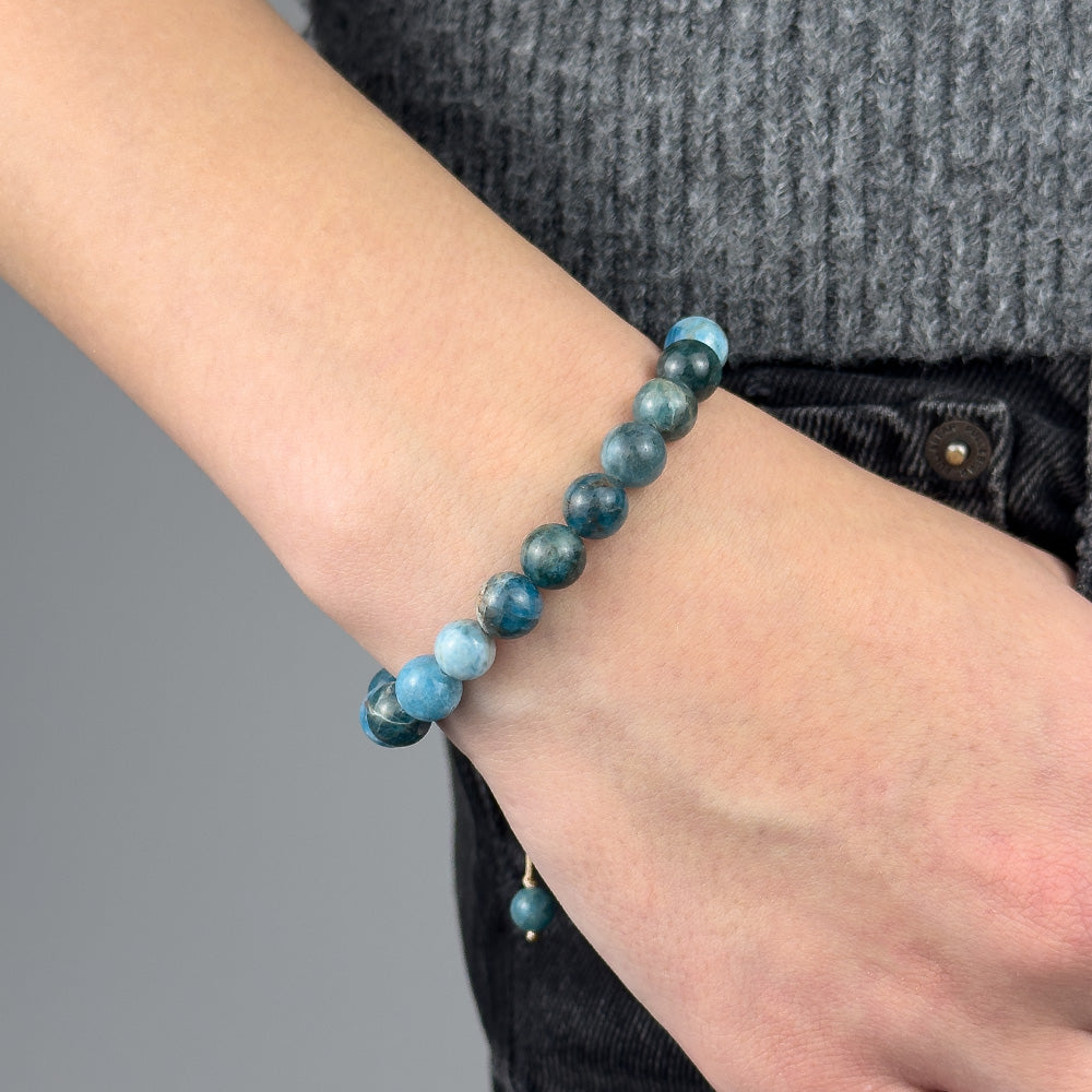 Blue beaded bracelet on a wrist with a gray background