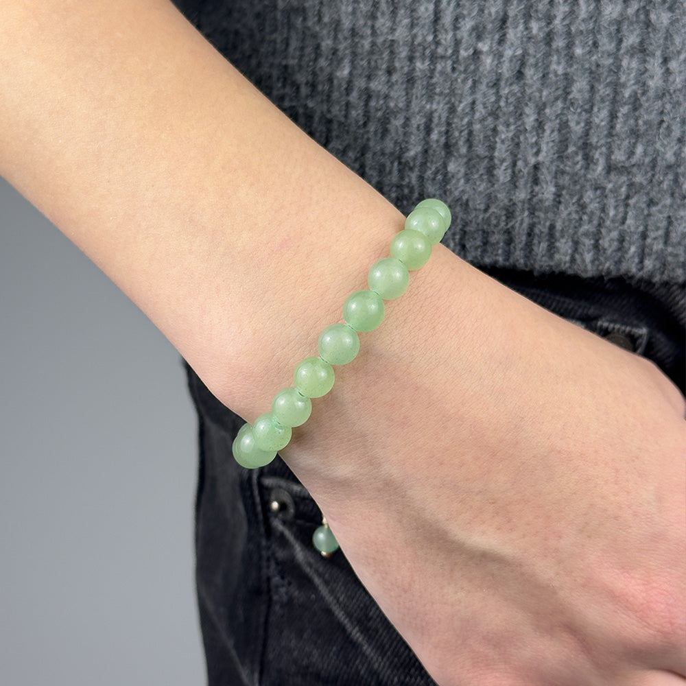 Green beaded bracelet on a wrist with a blurred background