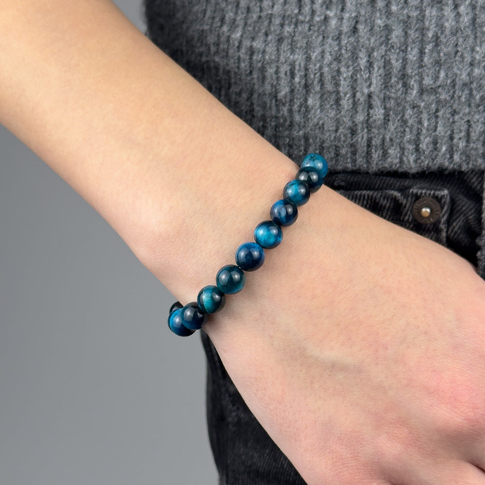 Blue beaded bracelet on a wrist with a gray background