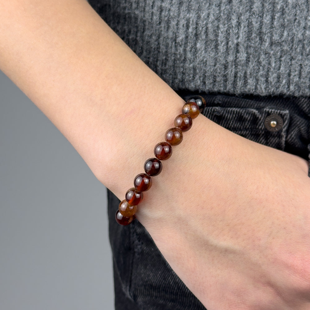 Close-up of a person's wrist wearing a brown beaded bracelet on a gray background