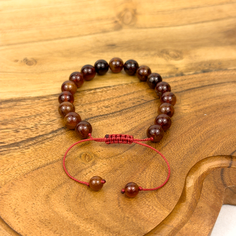 Brown beaded bracelet with a red string on a wooden surface