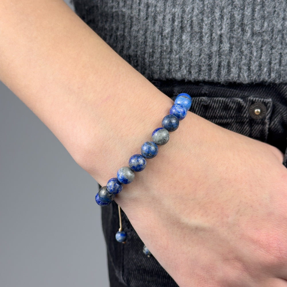 Person wearing a blue beaded bracelet on a blurred background