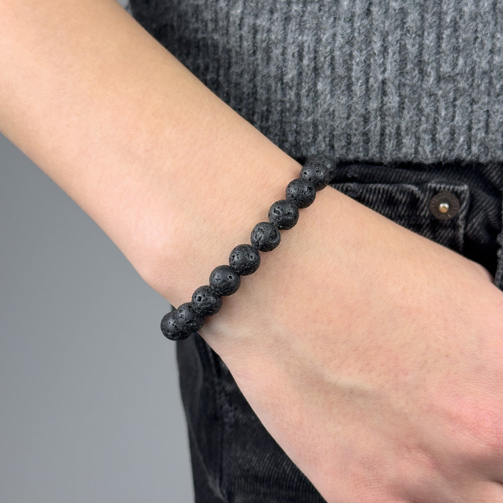 Black beaded bracelet on a wrist with a gray background