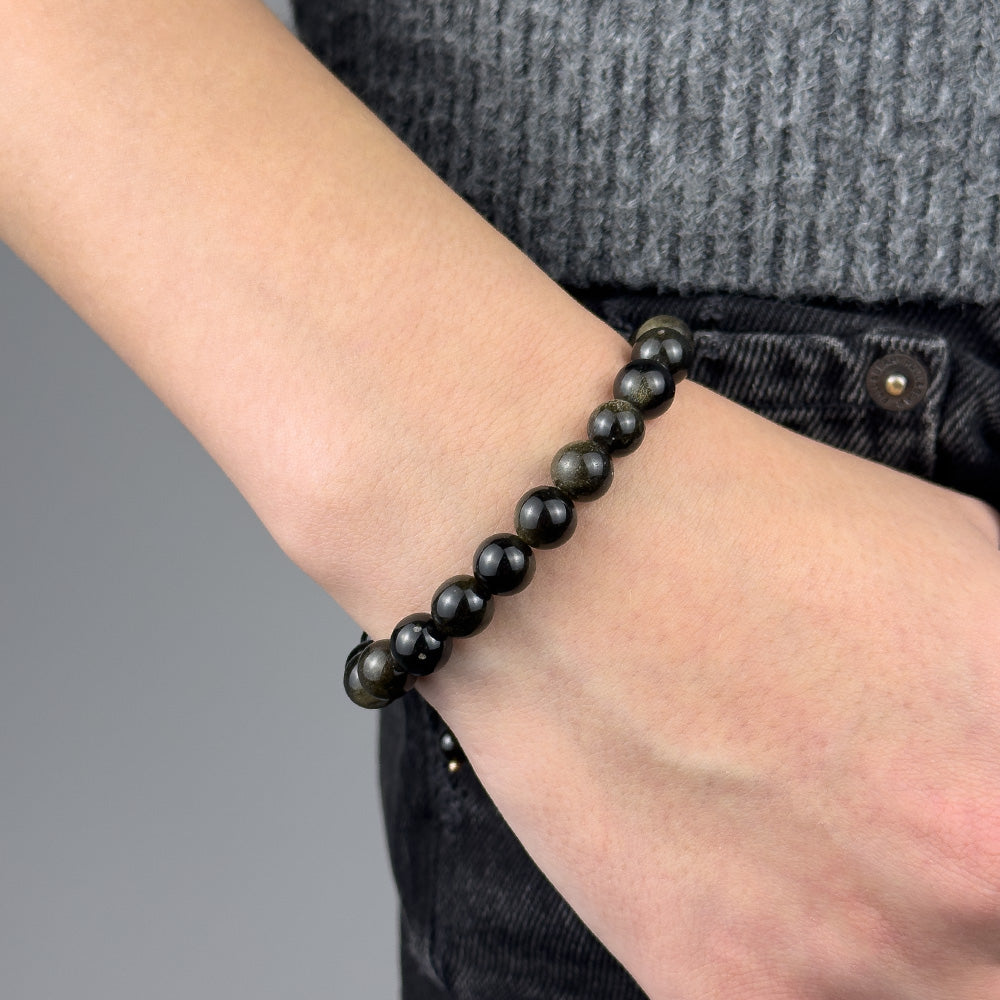 Person wearing a black beaded bracelet on a blurred background