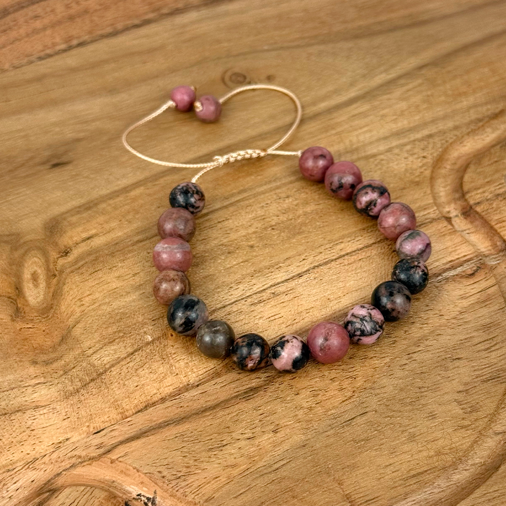 Beaded bracelet with pink and black beads on a wooden surface