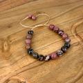 Beaded bracelet with pink and black beads on a wooden surface