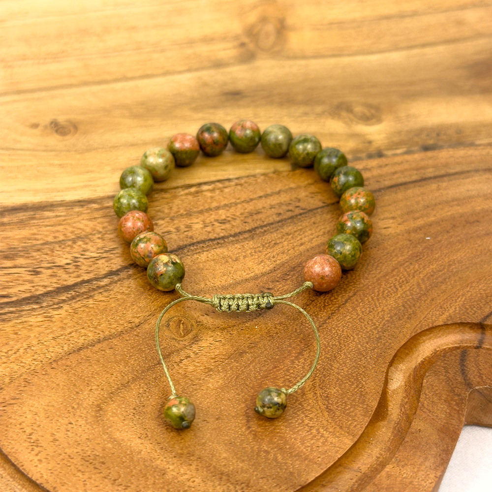 Beaded bracelet with green and brown stones on a wooden surface